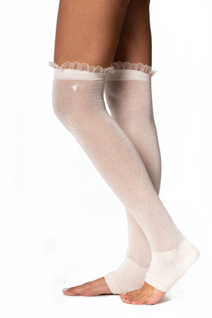Side view of ivory cotton over the knee legwarmer with a fitted heel and ruffle trim on the top seam.