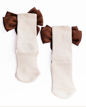 Cream grip socks with large brown bows on a white background