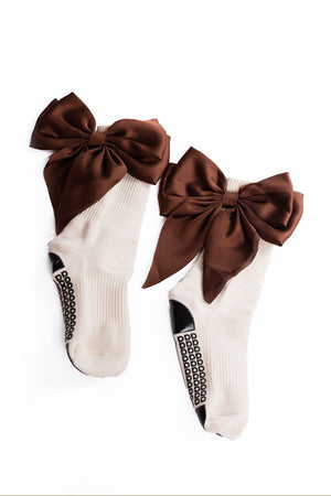 Cream grip socks with large brown bows on a white background