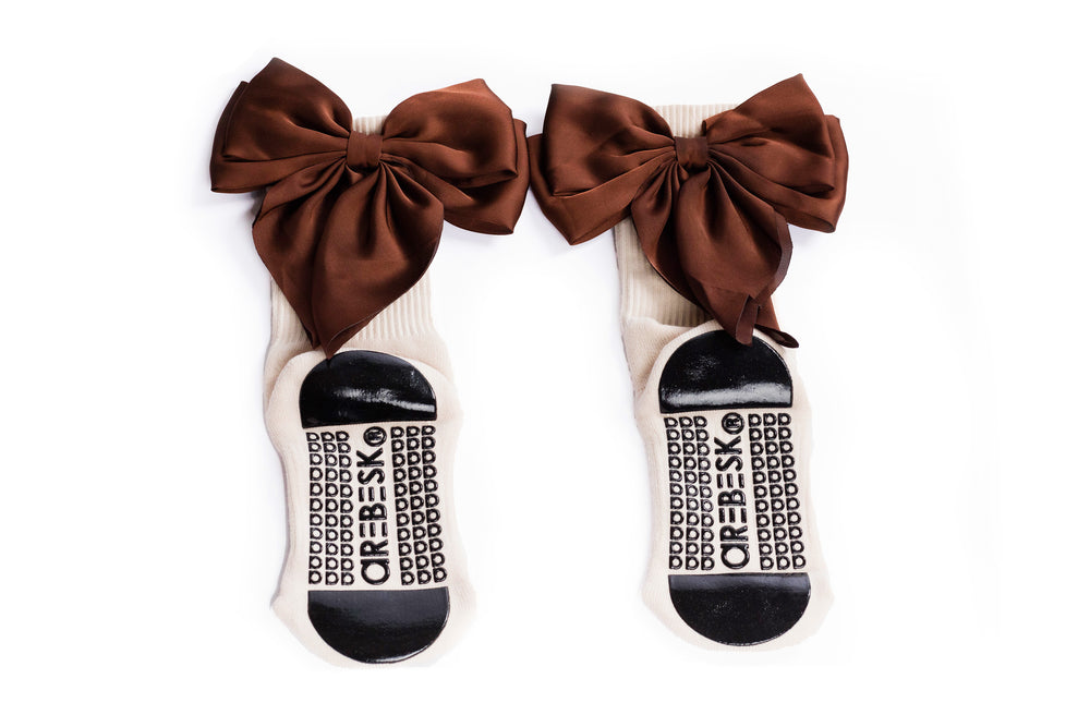 Cream grip socks with large brown bows on a white background