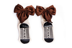 Cream grip socks with large brown bows on a white background