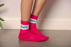 Close up shot of fuchsia crew socks with white stripe. Stripe accented with 'Pilates Queen' decorative text. 