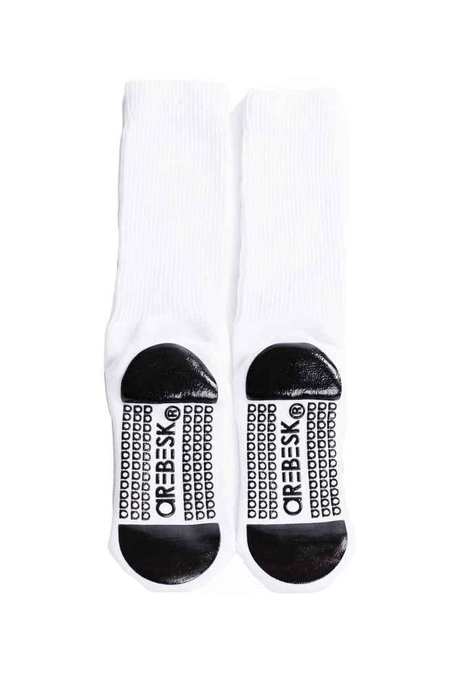 White crew socks with black grip on a white background