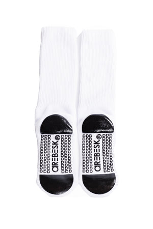 White crew socks with black grip on a white background