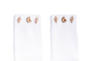 Close up detail of gold seashell jewels adorned to the white cuff of the grip sock.