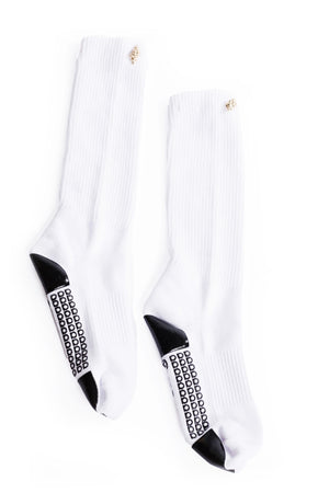 White grip socks with gold seashell decoration on the cuff laying on a white background.