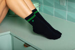 Close up of navy crew grip socks with green stripes.