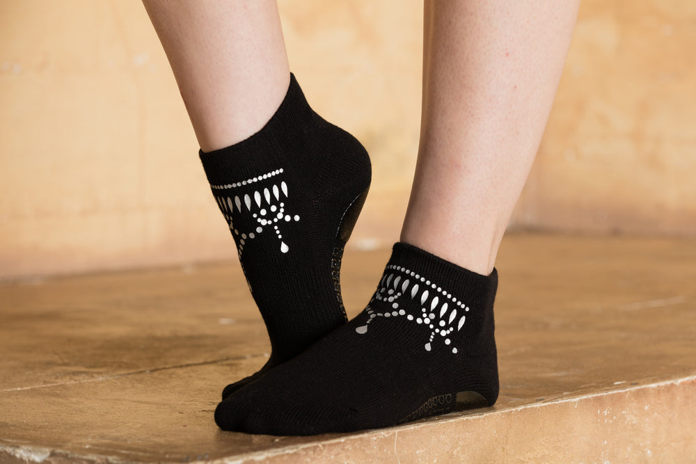 Side view of black ankle sock with silver metallic anklet silk screening.
