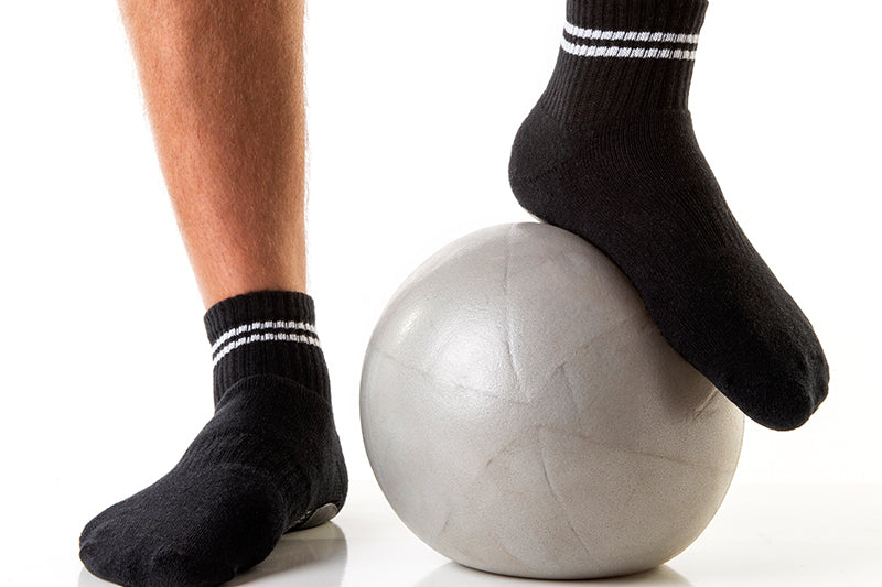 
            
                Load image into Gallery viewer, Men&amp;#39;s black low crew socks with white stripes and white triangular Arebesk logo, pictured with gray exercise ball.
            
        